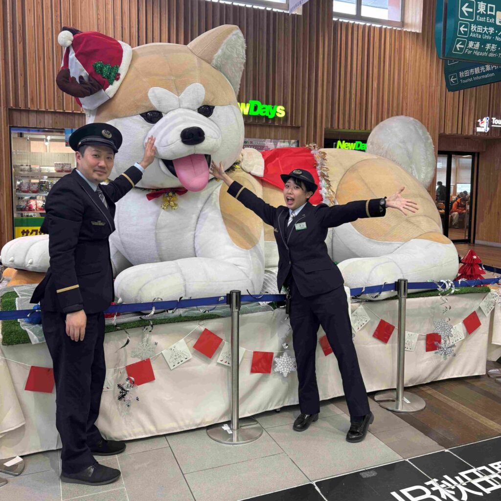 Train station staff in front of Akita dog statue